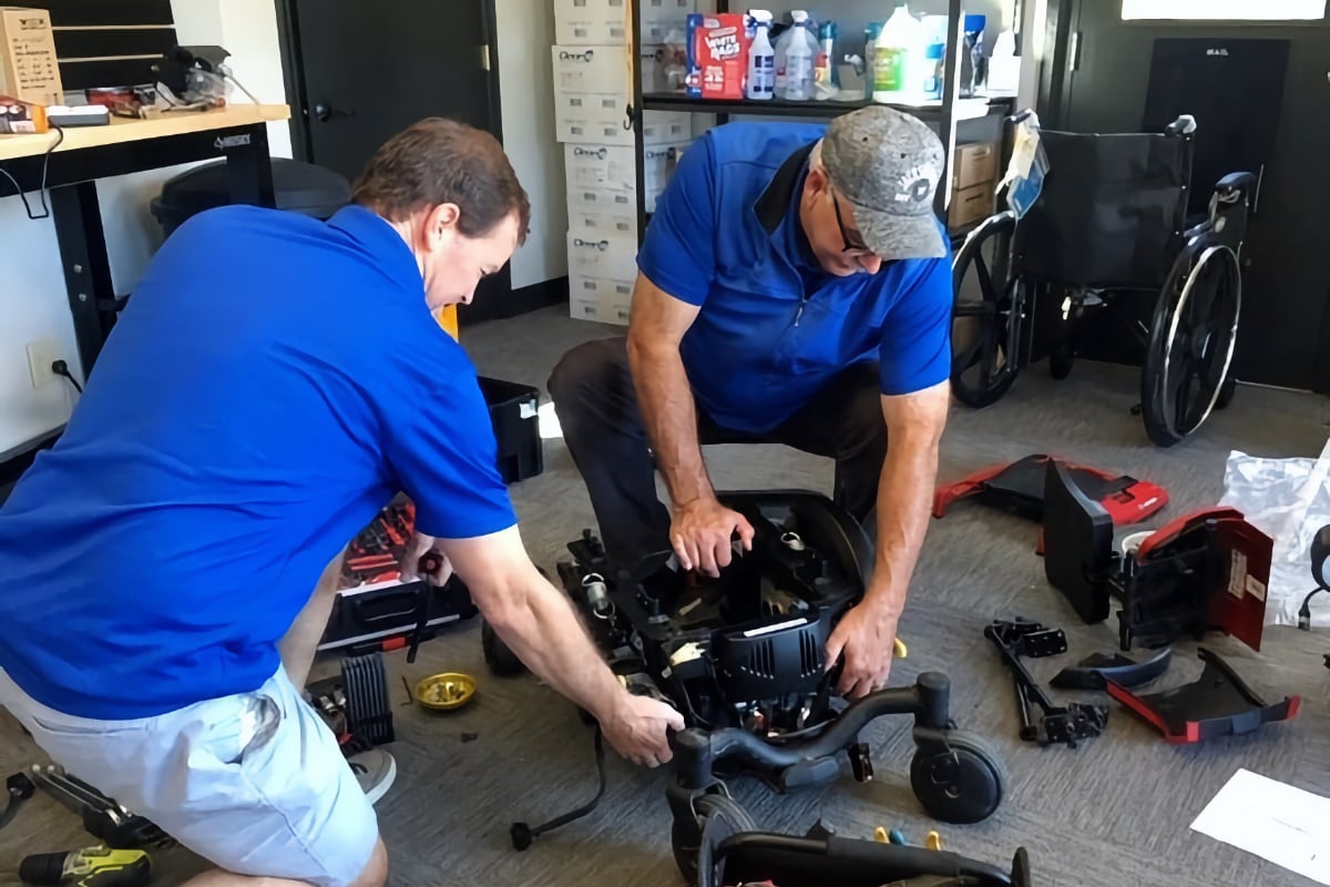 T-Town Mobility repairmen in blue shirts working on a wheelchair