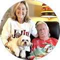 couple in Christmas sweaters holding a small dog